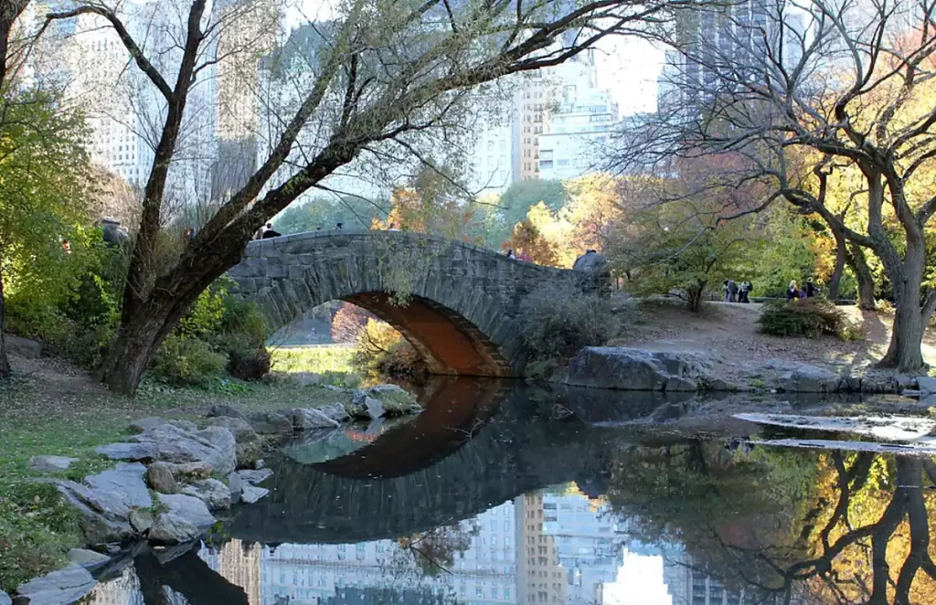 Gapstow Bridge, a ponte de pedra no Central Park refletida no lago durante o outono em Nova York