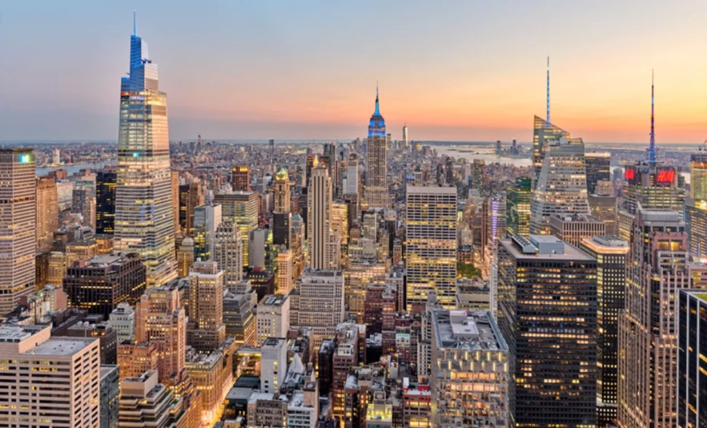 Skyline de Manhattan ao entardecer, com arranha-céus iluminados e vista urbana de Nova York