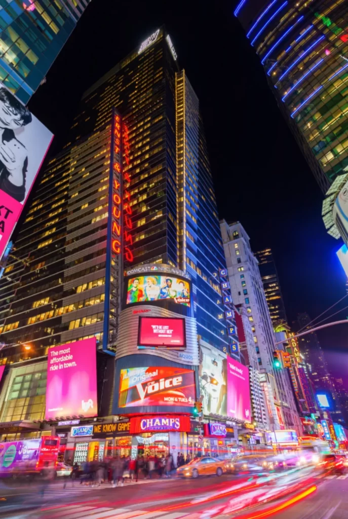 Times Square à noite com painéis luminosos e movimento intenso no coração de Nova York