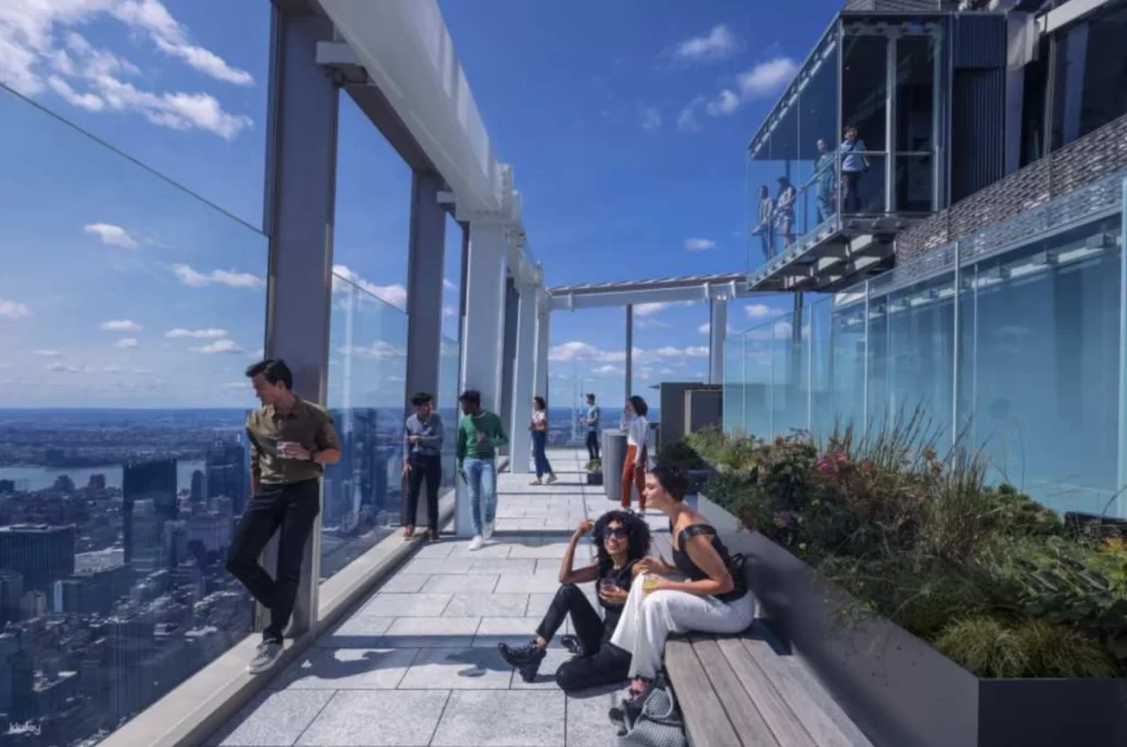 Terraço externo do Summit One New York com visitantes apreciando a vista panorâmica da cidade.