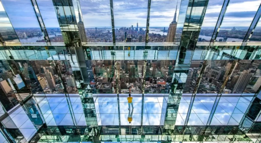 Deck espelhado do Summit One New York com vista panorâmica e reflexos do skyline de Nova York.