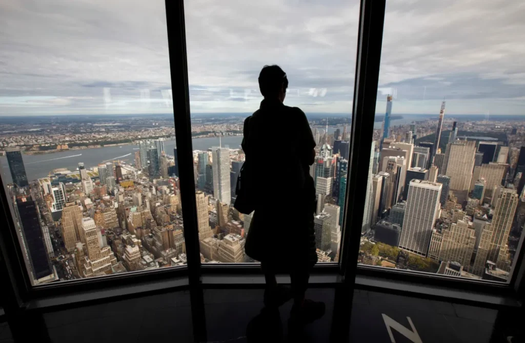 Visitante admirando Manhattan do observatório do 102º andar.