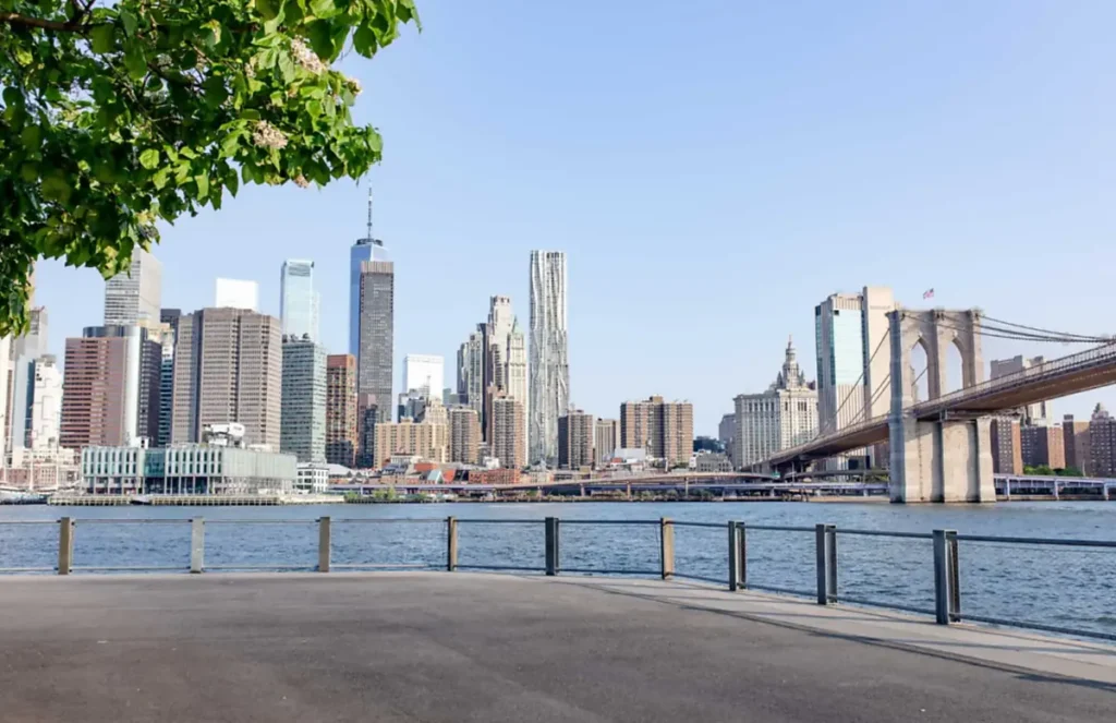 Brooklyn Bridge e skyline de Lower Manhattan vistos do waterfront do Brooklyn em dia ensolarado.