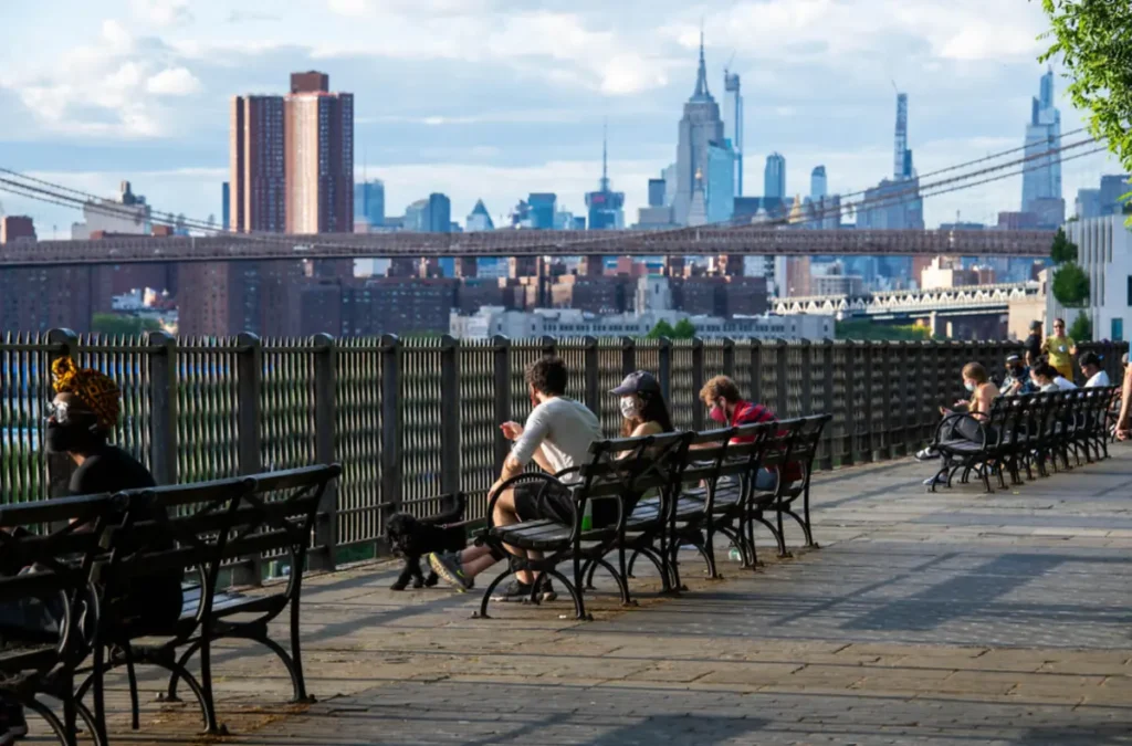 Visitantes descansam na Brooklyn Heights Promenade diante da vista de Manhattan.