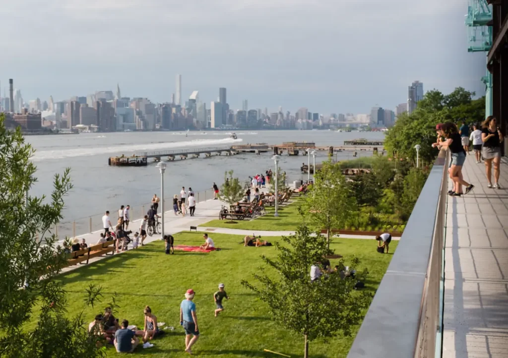 Visitantes aproveitam o Domino Park, no waterfront de Williamsburg, com Manhattan ao fundo.