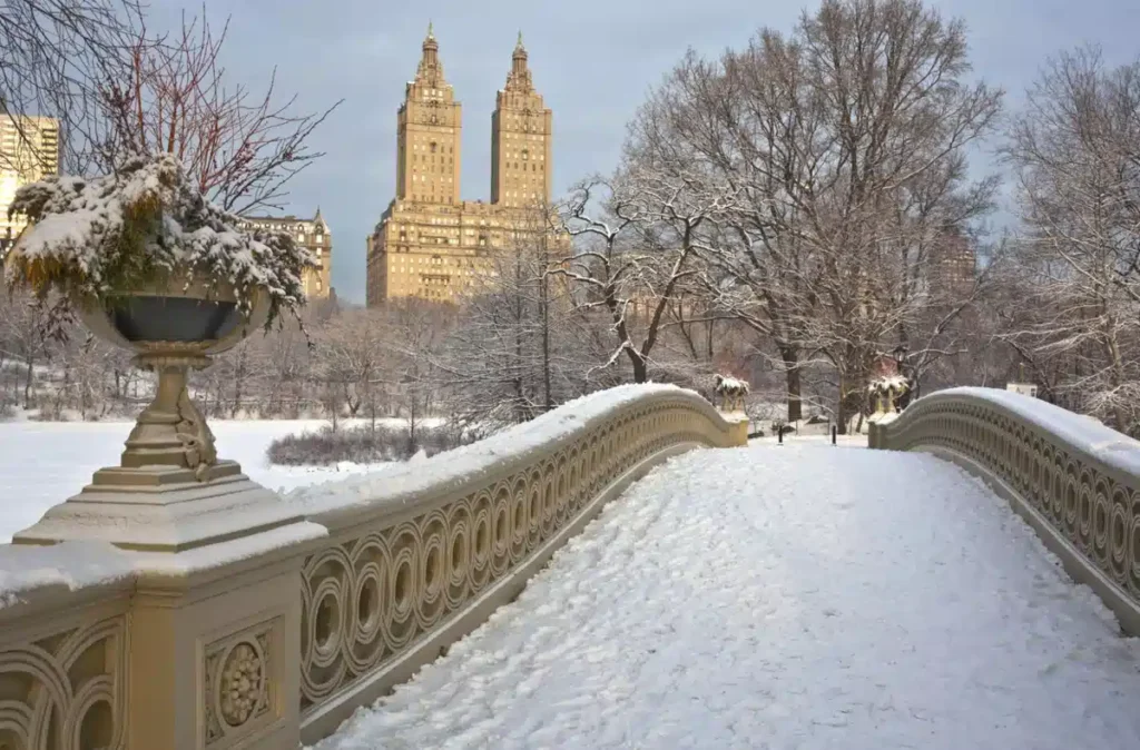 O Central Park coberto de neve é um dos cenários mais bonitos do inverno em Nova York. A histórica Bow Bridge, com o edifício San Remo ao fundo, oferece uma paisagem encantadora em Manhattan.