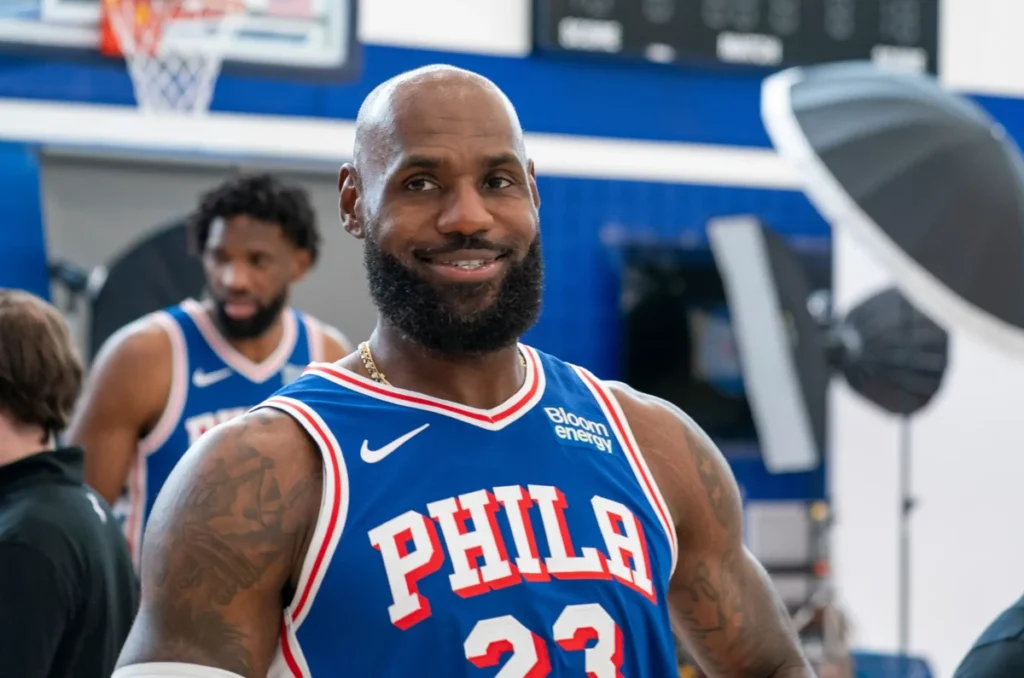LeBron James aparece vestindo a camisa 23 do Philadelphia 76ers em imagem ilustrativa. O astro da NBA, conhecido por sua trajetória no Cleveland Cavaliers, Miami Heat e Los Angeles Lakers, é um dos maiores jogadores da história do basquete.